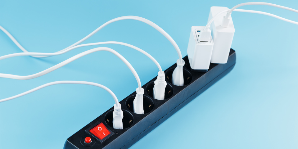 Surge protector with connected white wires of electrical appliances on a blue background. Free space